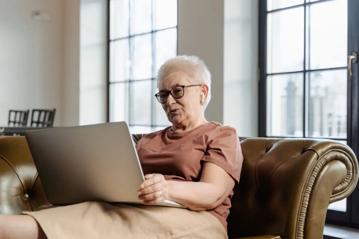 An elderly woman reading about My Aged Care on her laptop